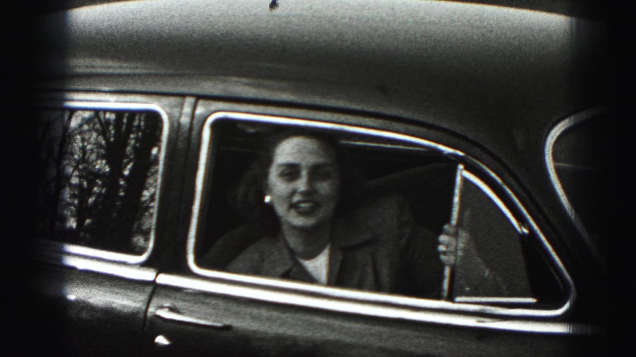 In Harrisburg metadata context, a woman in a collared jacket sits in a vintage car and faces the camera through the open window.