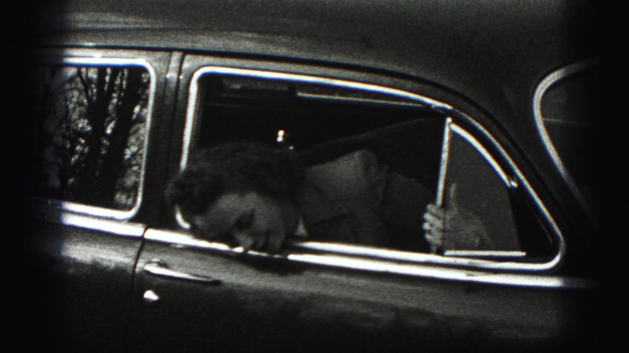 Woman bending down inside the rear side window of an older car.