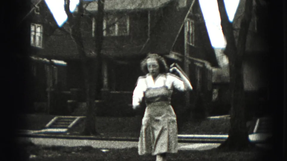 A woman in a light dress holds a golf club near her shoulder in a Harrisburg yard, with houses and tree trunks behind her.
