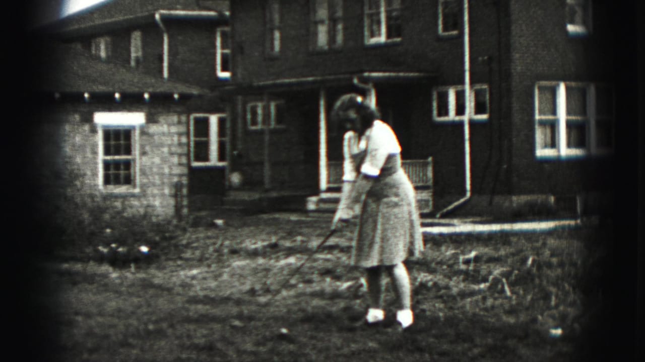 In Harrisburg, Pennsylvania home-movie footage from 1975, a woman prepares a golf shot in a backyard near a brick house.