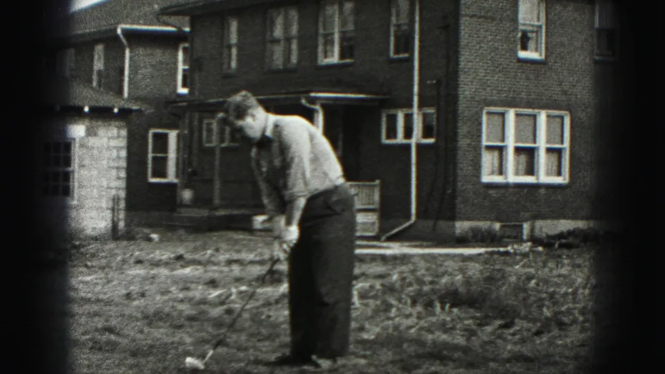 The man continues his backyard golf stance outside a Harrisburg brick residence in 1975 home-movie footage.