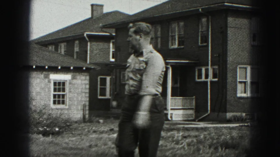 The man is seen in side view with the club lowered as he moves near the brick house exterior in Harrisburg.