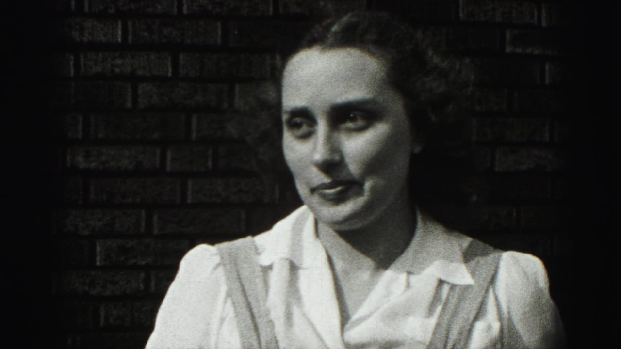 A young woman in a white blouse and suspenders faces the camera against a brick wall in Harrisburg, Pennsylvania, 1975.