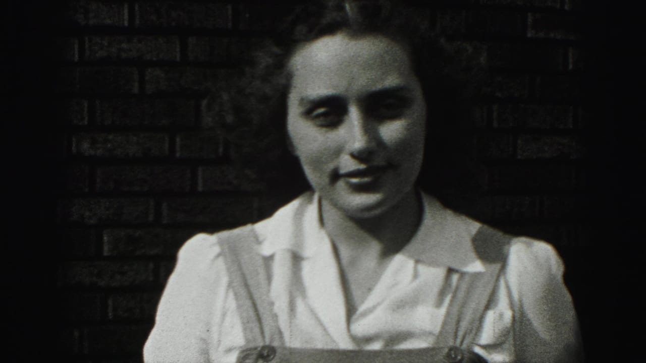 Young woman facing the camera with a slight smile against brickwork.
