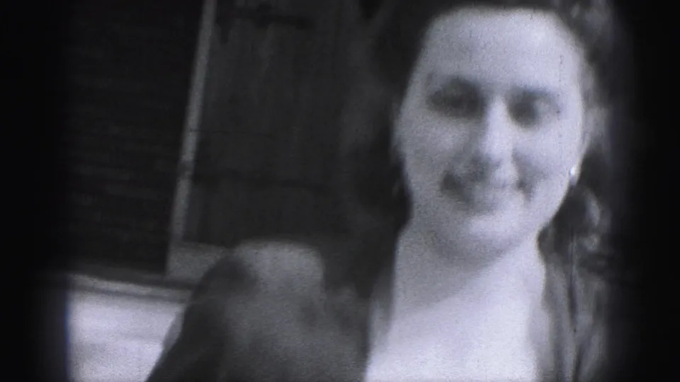 A closer 1975 Harrisburg frame shows the woman smiling near the brick exterior and entrance area.
