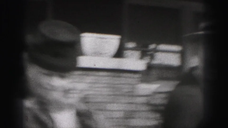 A soft, handheld 8mm frame catches blurred movement near brick steps and the edge of a hat.