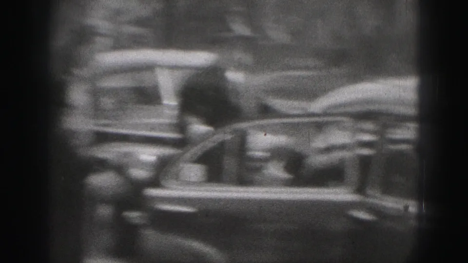 A woman appears to move out of or beside an open car door in 1975 Harrisburg street footage, partly obscured by soft focus.
