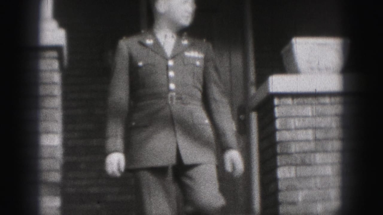 The uniformed man approaches the camera from the porch area, with brick columns and a doorway visible behind him.