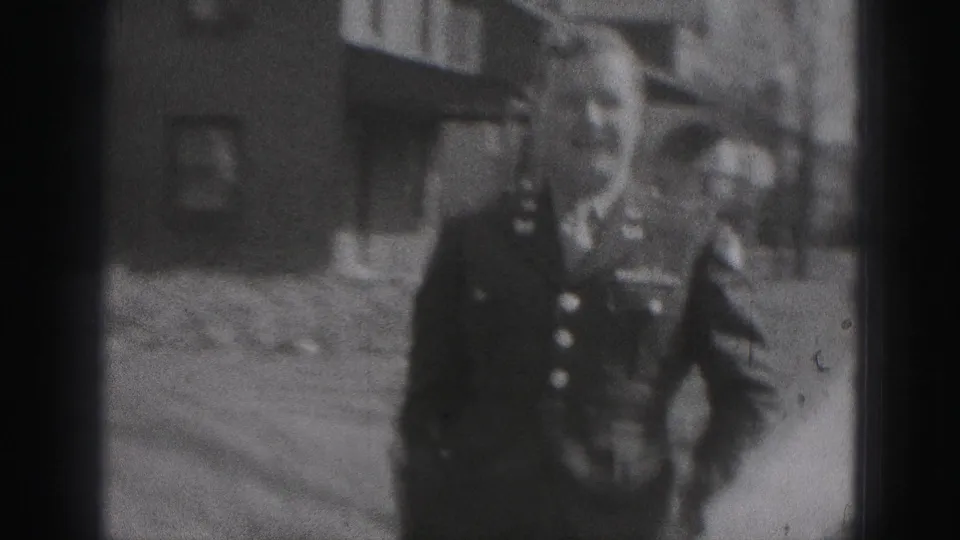 A closer 1975 Harrisburg frame shows a uniformed police officer near residential houses, with his face and insignia partly visible.