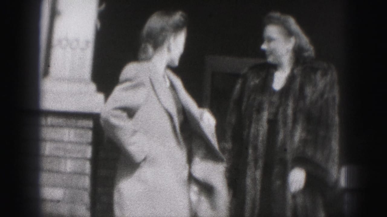 Two women in coats stand near a brick building entrance.