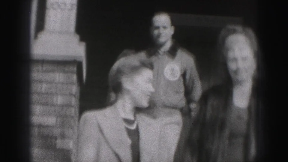 Two women and a man stand together outside a building in the Harrisburg 1975 home-movie scene.