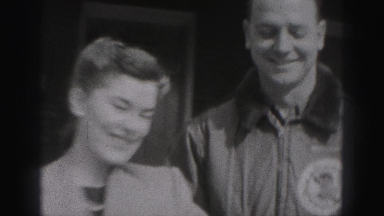 In 1975 Harrisburg home-movie footage, a woman and man smile toward the camera with soft focus and dark frame edges.