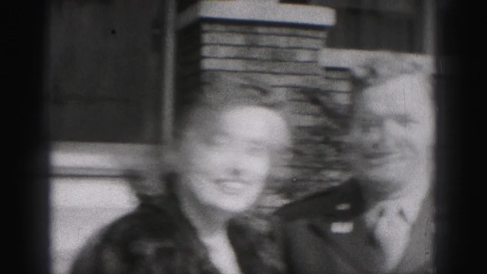 The woman smiles close to the camera while the uniformed man stands beside her outside a Harrisburg residence.