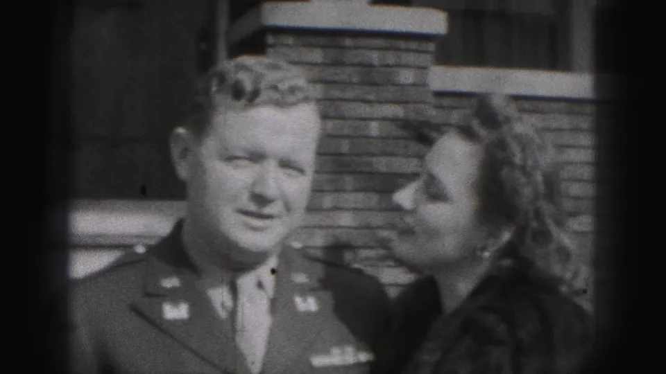 A uniformed man looks toward the camera as the woman in a fur coat turns toward him outside the Harrisburg house.