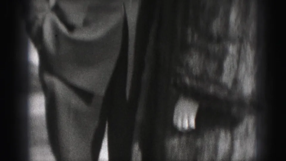 A close, partially cropped Harrisburg home-movie frame shows the couple standing together, with the fur coat and uniform visible.