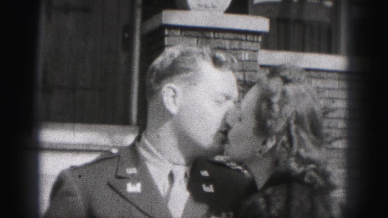 A soldier and woman kiss outside a brick home in the 1975 Harrisburg, Pennsylvania 8mm footage.