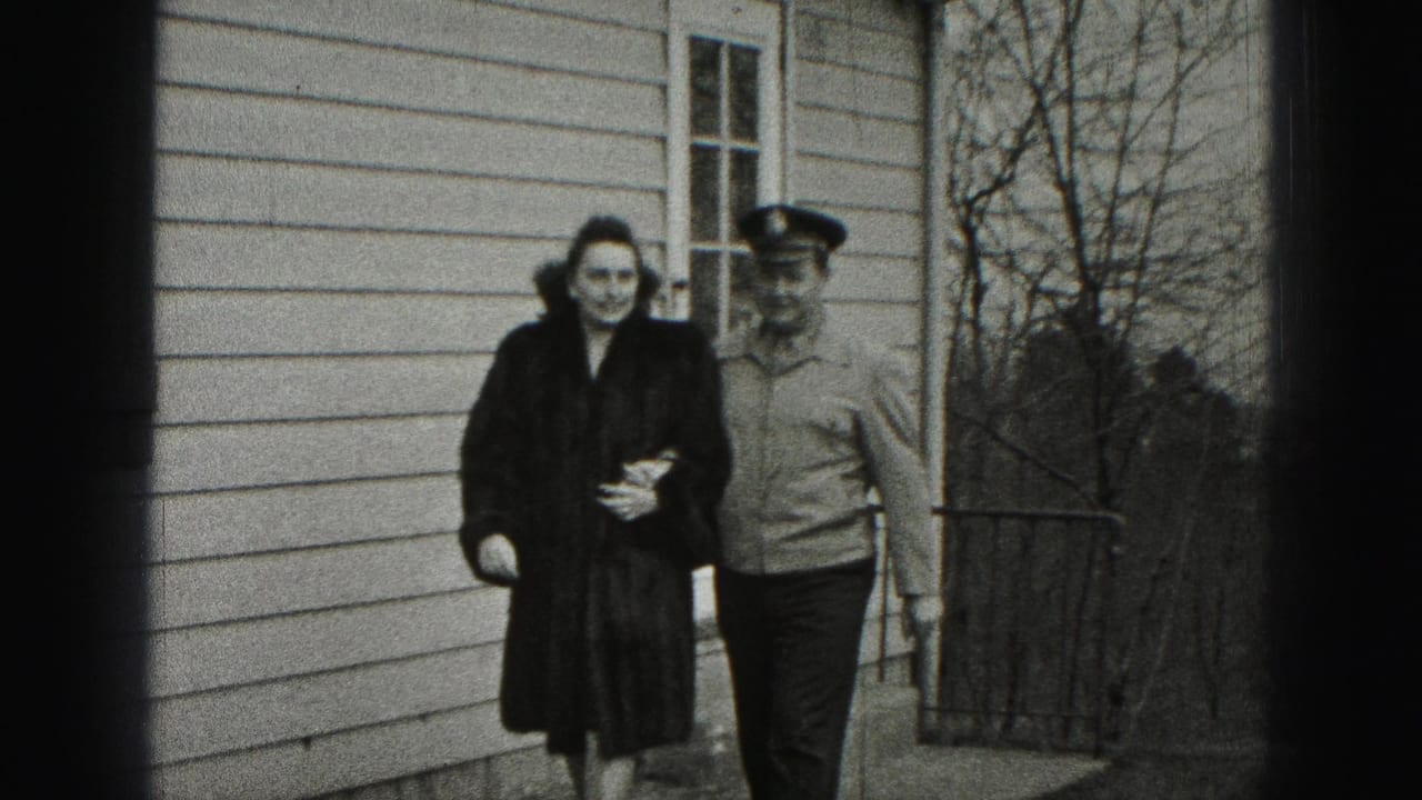 In Harrisburg, Pennsylvania home-movie footage, a woman in a dark fur coat walks beside a uniformed man along a residential walkway.