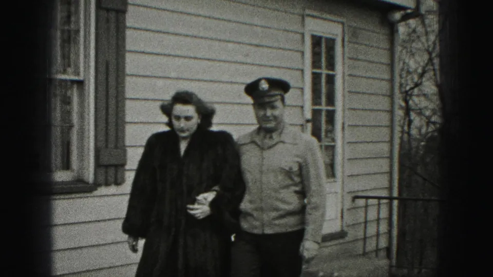 The pair continues arm-in-arm past a light-sided Harrisburg house, with the uniformed man close beside the woman.