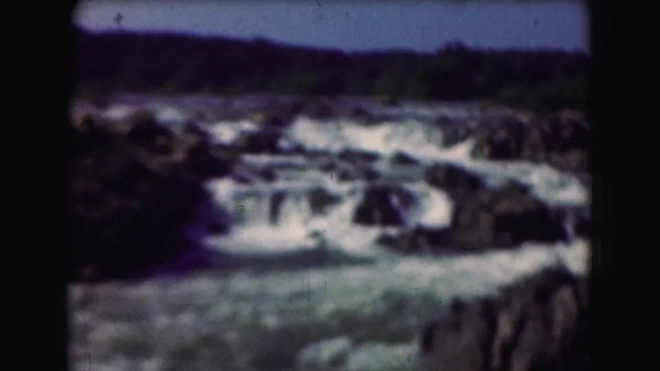 Wider 8mm frame of turbulent whitewater, dark rocks, and a tree-lined bank in the Washington, DC metadata location.