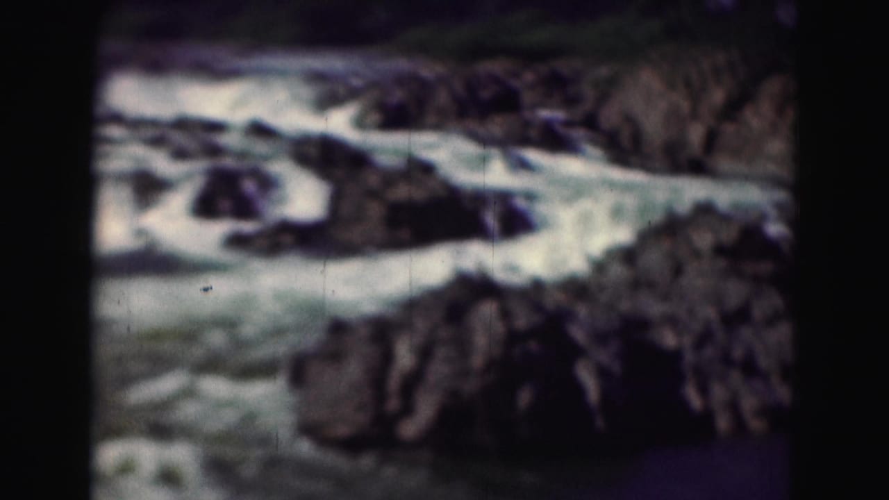 Rocky river rapids fill the frame in this 1975 Washington, DC-area 8mm travel shot, with visible grain and slight color fading.