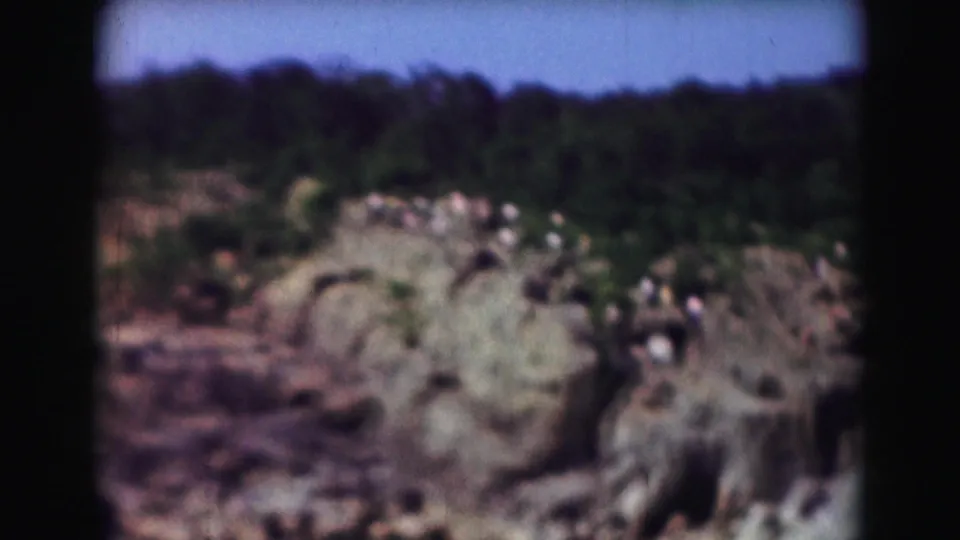 Distant visitors appear on a rocky outcrop near the river in this 1975 Washington, DC-area 8mm home-movie frame.