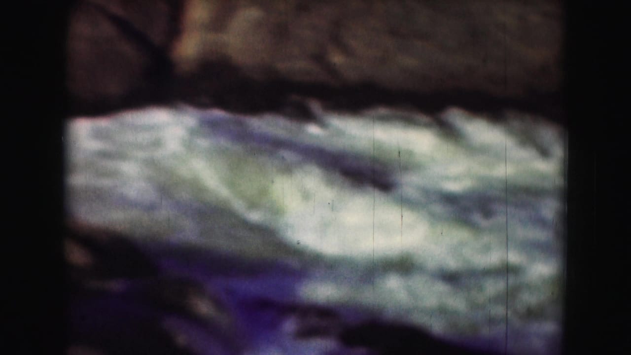 1975 8mm Washington, DC-area footage showing blurred white water rapids framed by dark rocks and heavy film borders.