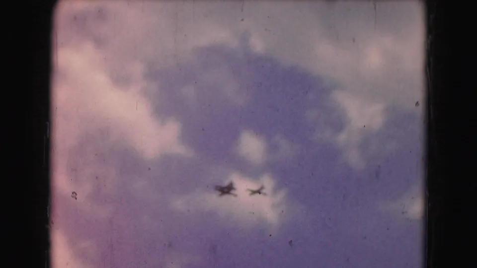 1975 8mm Washington, DC frame with three jet silhouettes in formation against a cloudy purple-blue sky.