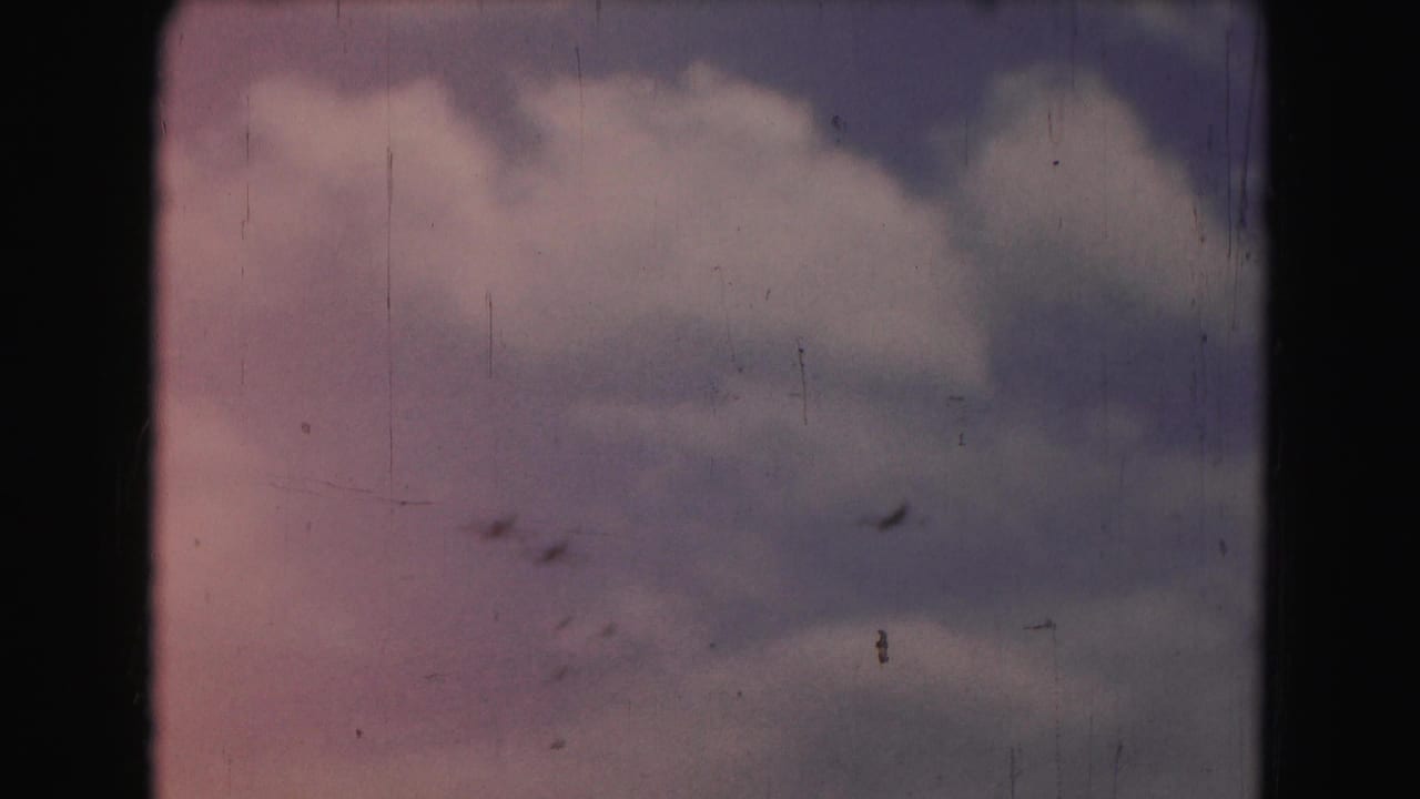 Tiny aircraft silhouettes are visible against a softly colored cloudy sky in the 1975 Washington, DC 8mm footage.