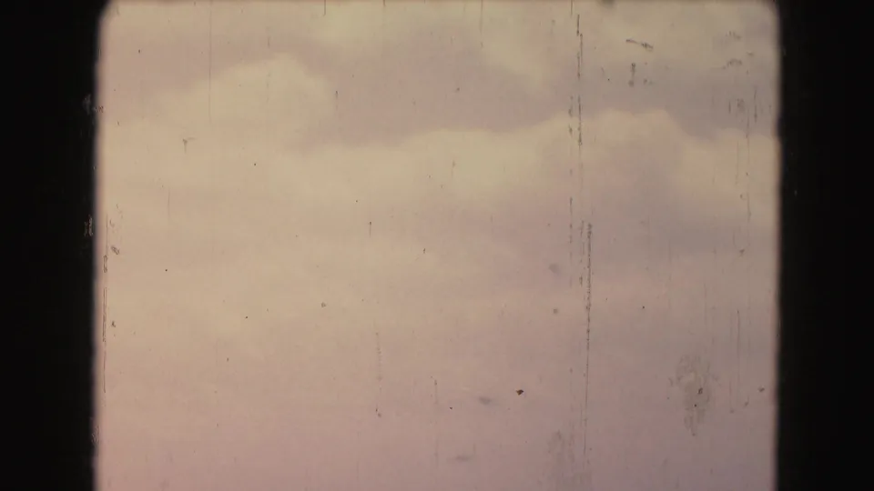 A pale clouded sky fills the final 1975 Washington, DC frame, with film scratches, dust, and faded color prominent.