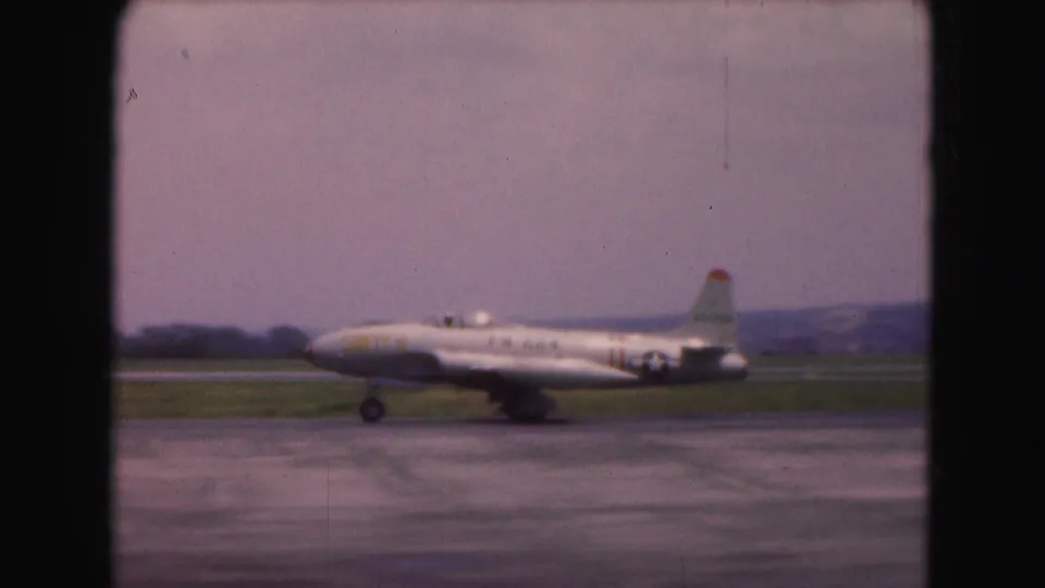 The airliner reaches the right side of the frame while taxiing on a wet Washington, DC runway in 1975 home-movie footage.