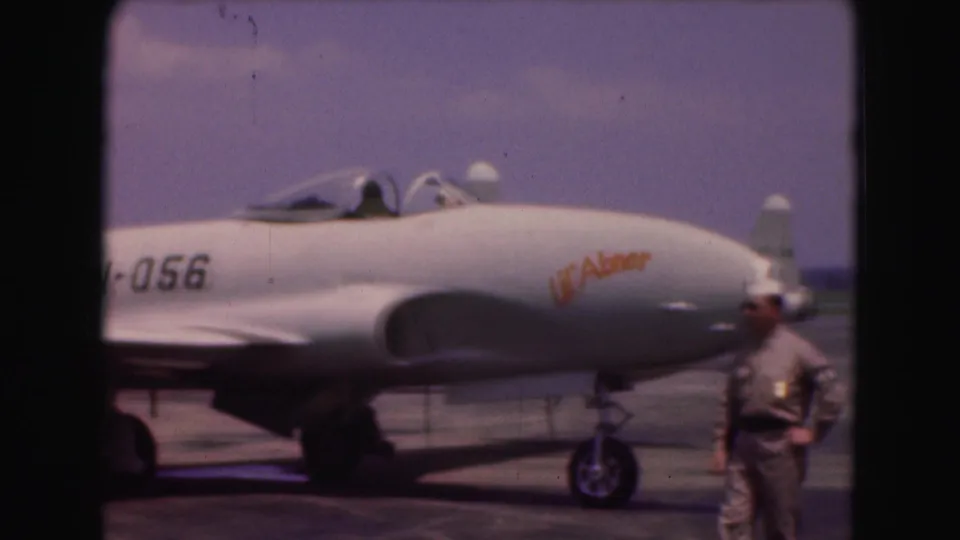 1975 Washington, DC 8mm side view of the military jet showing PN-056 and Lil' Abner markings near a uniformed man.