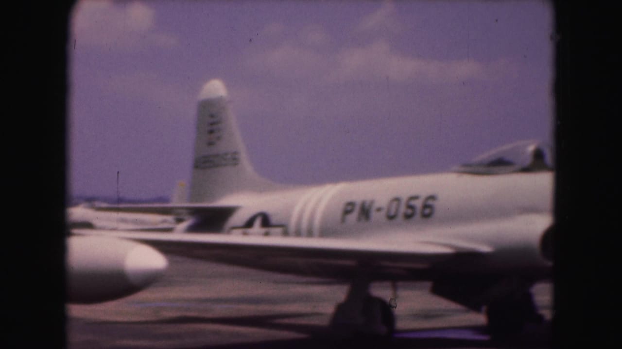 1975 8mm Washington DC visit footage showing a close side view of a white military jet marked PN-056 on an airfield tarmac.