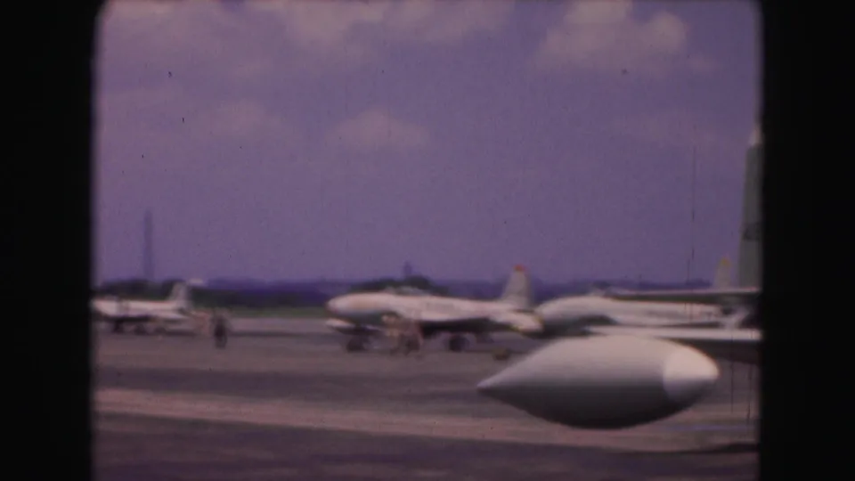 1975 8mm Washington DC airfield footage showing parked military jets and a prominent white foreground aircraft shape.