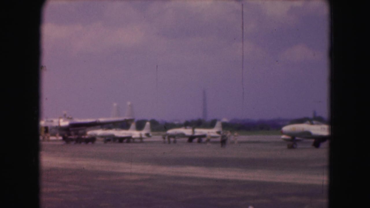 Several military jets parked on a tarmac under a hazy sky.