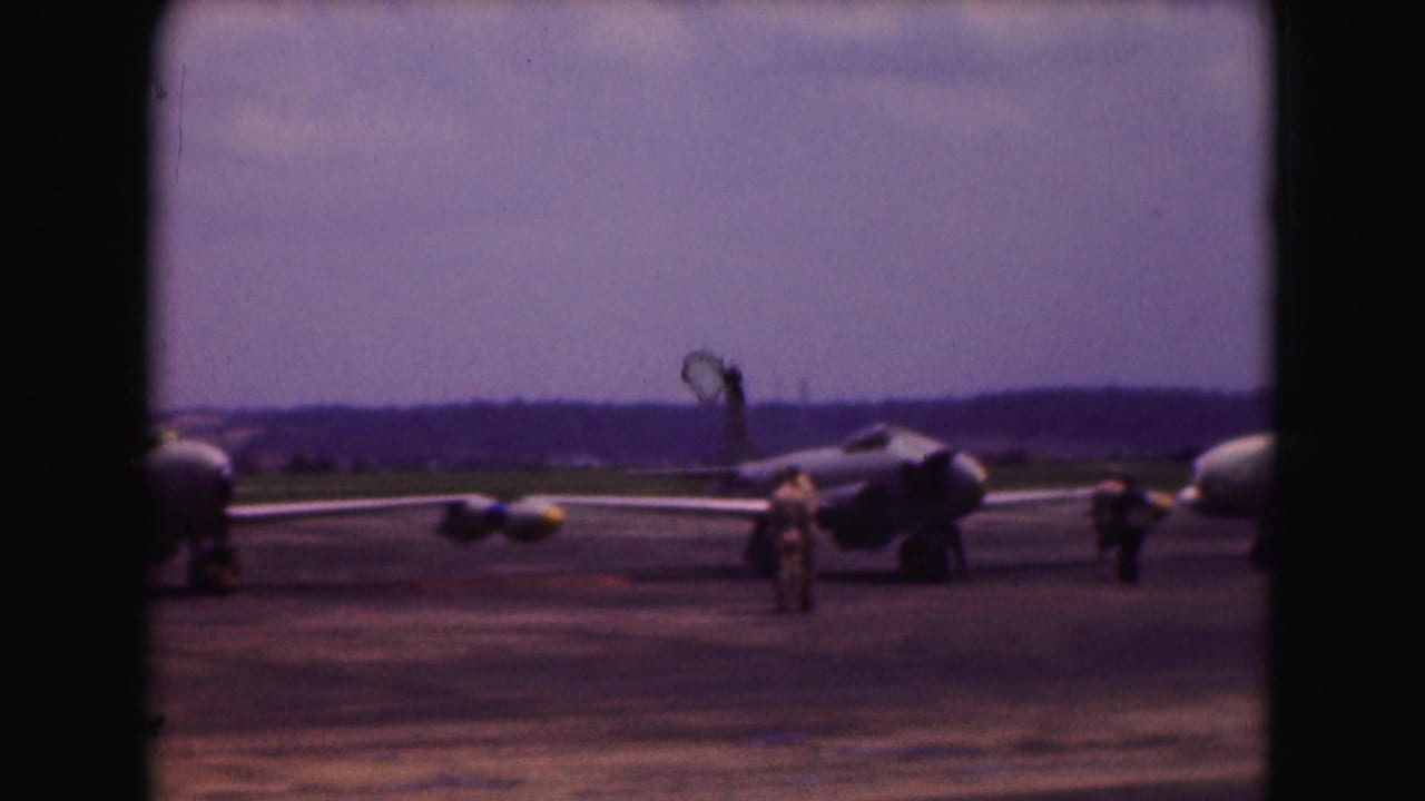 Parked jet aircraft on a tarmac with several ground crew figures nearby.