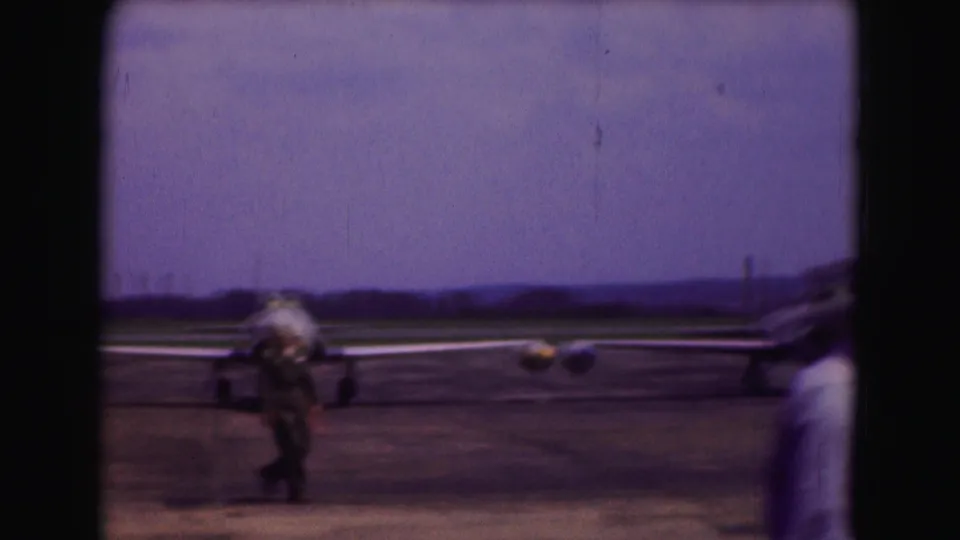 Soft 8mm frame of a jet aircraft and a walking ground crew member on a 1975 Washington DC airport tarmac.