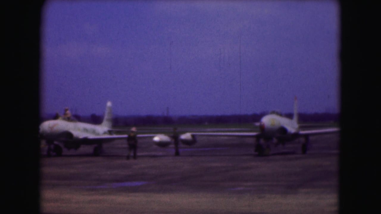 Military aircraft on a Washington, DC runway in 1975, with a ground crew member visible between the planes.