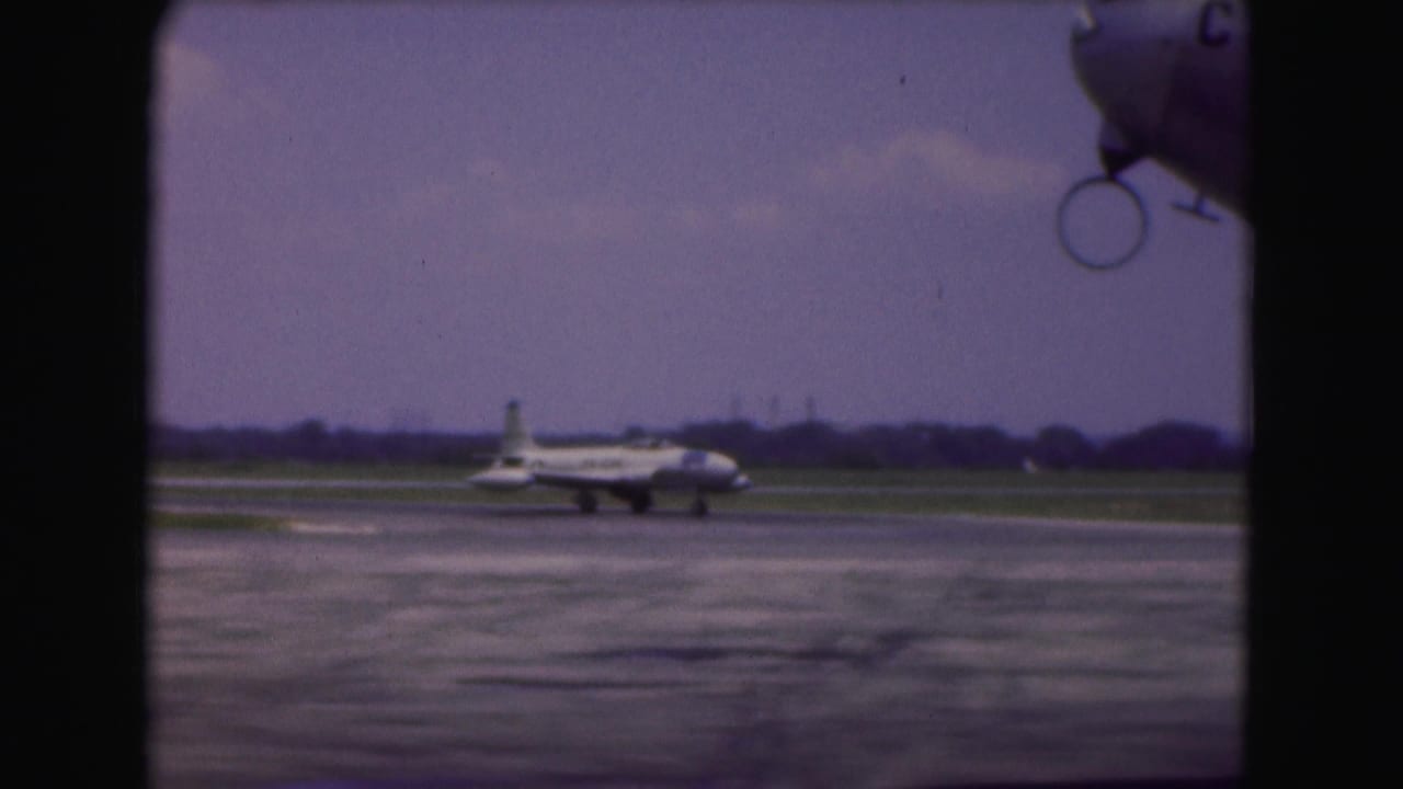 The taxiing aircraft appears farther across the Washington DC airport tarmac, with low grass and a distant horizon behind it.