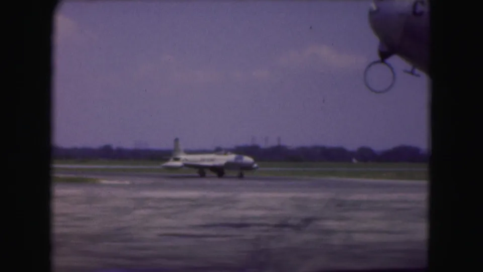 The taxiing aircraft appears farther across the Washington DC airport tarmac, with low grass and a distant horizon behind it.