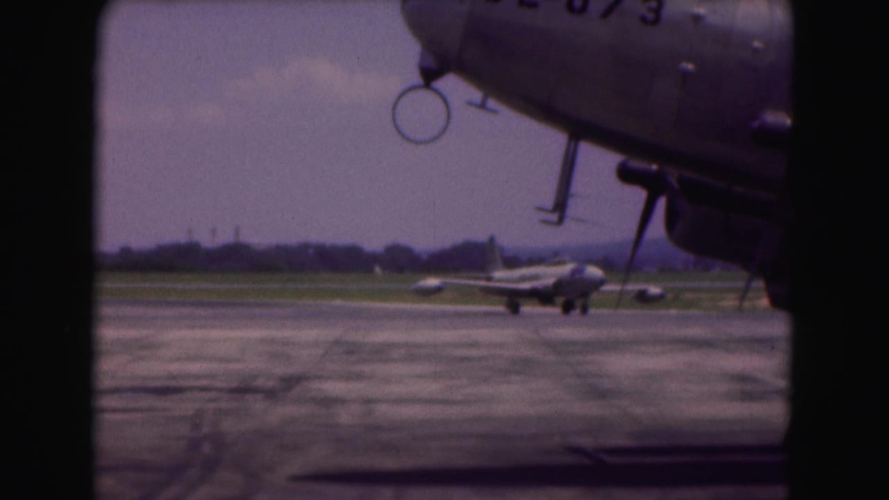 1975 Washington, DC-area airfield view with a foreground propeller aircraft and a smaller jet turning in the distance.