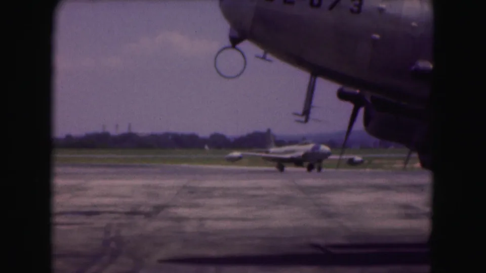 1975 Washington, DC-area airfield view with a foreground propeller aircraft and a smaller jet turning in the distance.