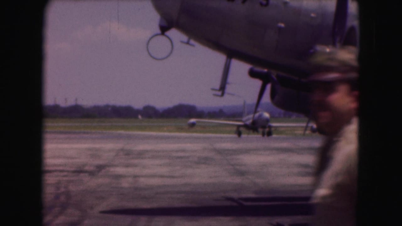 A jet taxis across the Washington, DC-area airfield while a uniformed man briefly enters the 8mm frame.