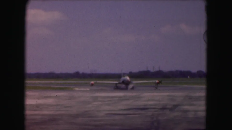 1975 Washington DC 8mm frame showing the small aircraft from the front as it taxis on runway pavement toward the camera position.