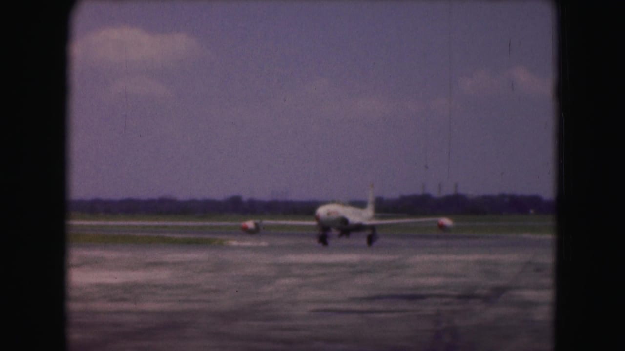 White military jet approaching on a runway under a cloudy sky.