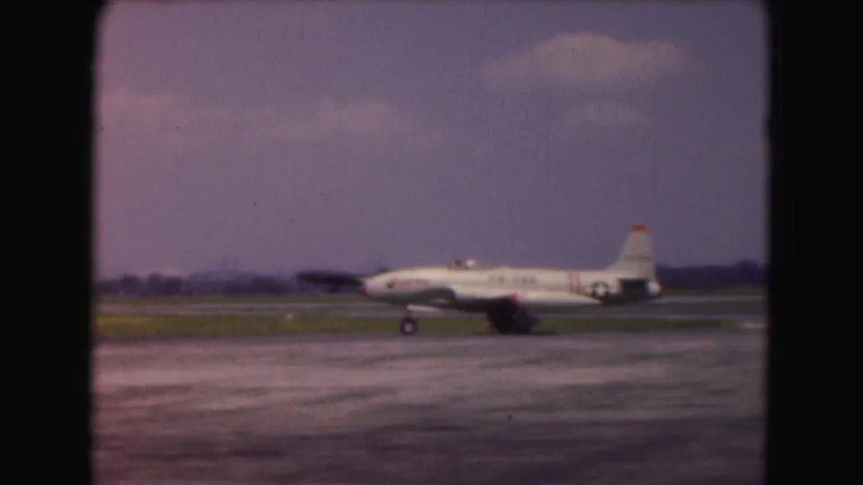 1975 Washington DC frame showing a white USAF jet on the runway with another aircraft faintly visible behind it.
