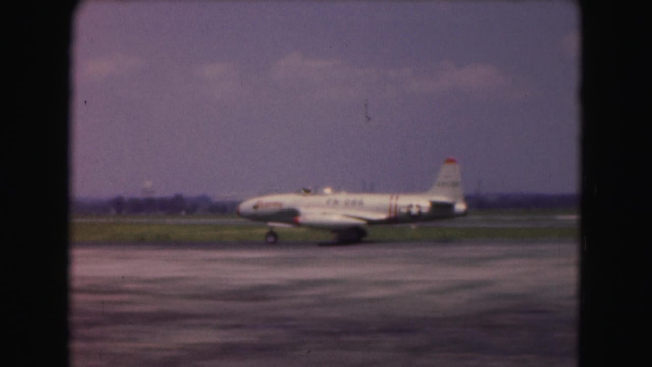 A white jet with U.S. Air Force style insignia appears in profile while taxiing at a Washington-area airport in 1975 footage.