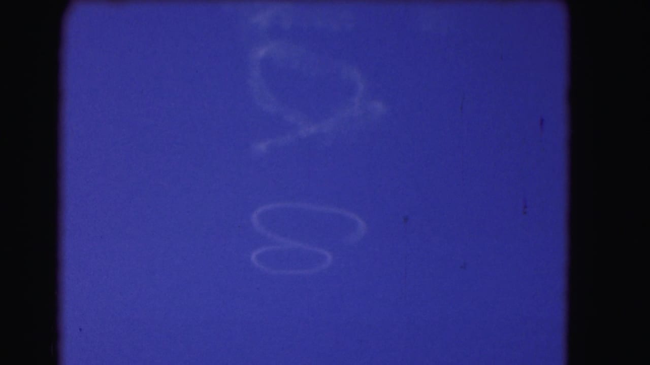 Blue sky with faint wispy cloud shapes and dark film borders.