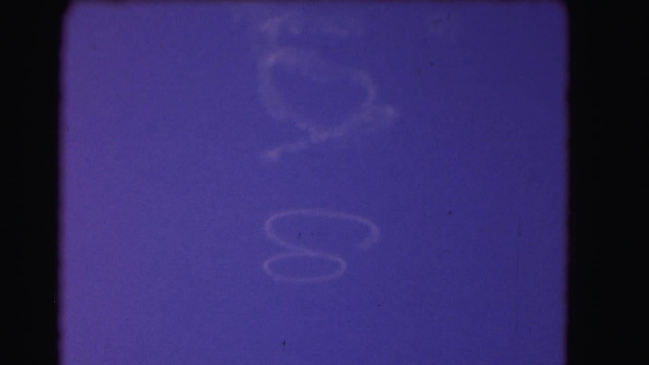 1975 8mm Washington, DC home-movie frame dominated by faded blue-magenta exposure, visible film gate edges, dust, and scratches.