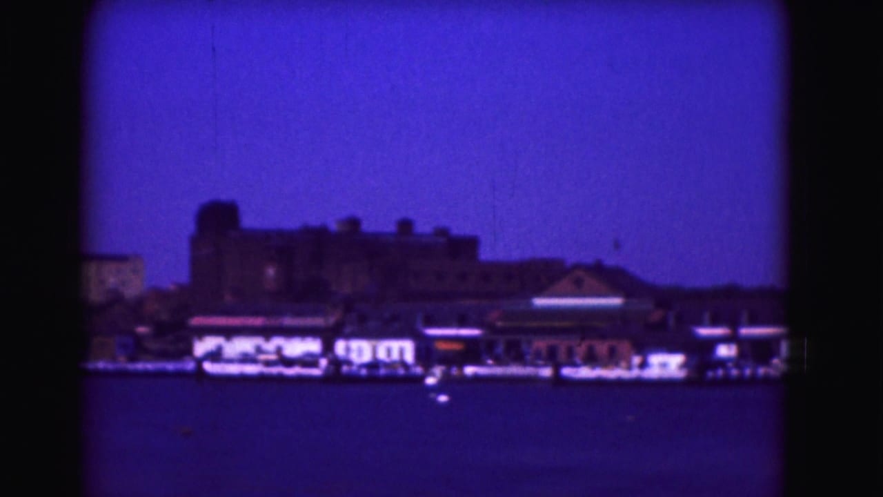 Waterfront buildings and small boats along the shoreline beneath a dark blue sky.