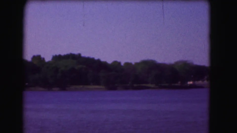 1975 Washington, DC river view with open water, trees, and faint shoreline structures in soft 8mm color.